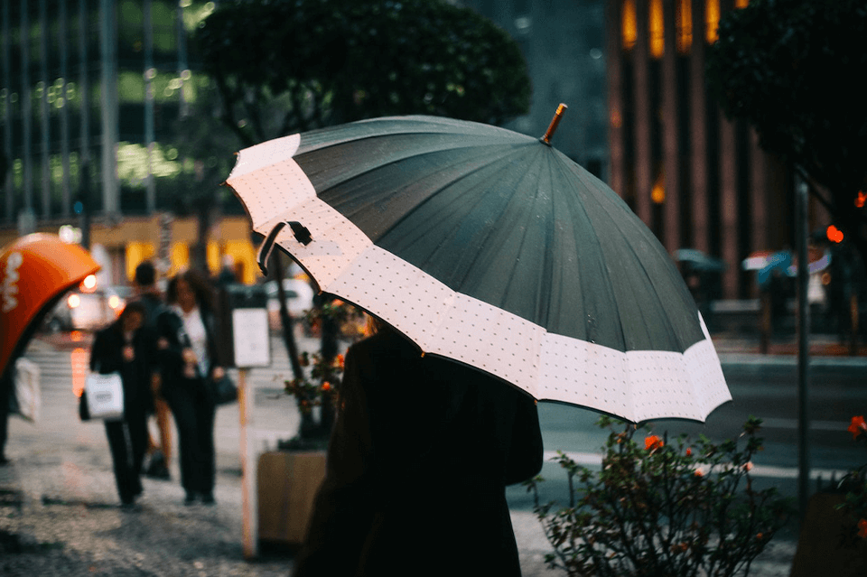 Woman walking on the street while holding an umbrella over her