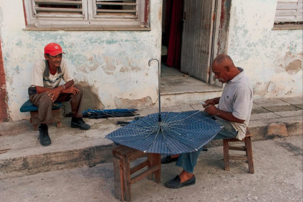 man repairing umbrella while other man watches