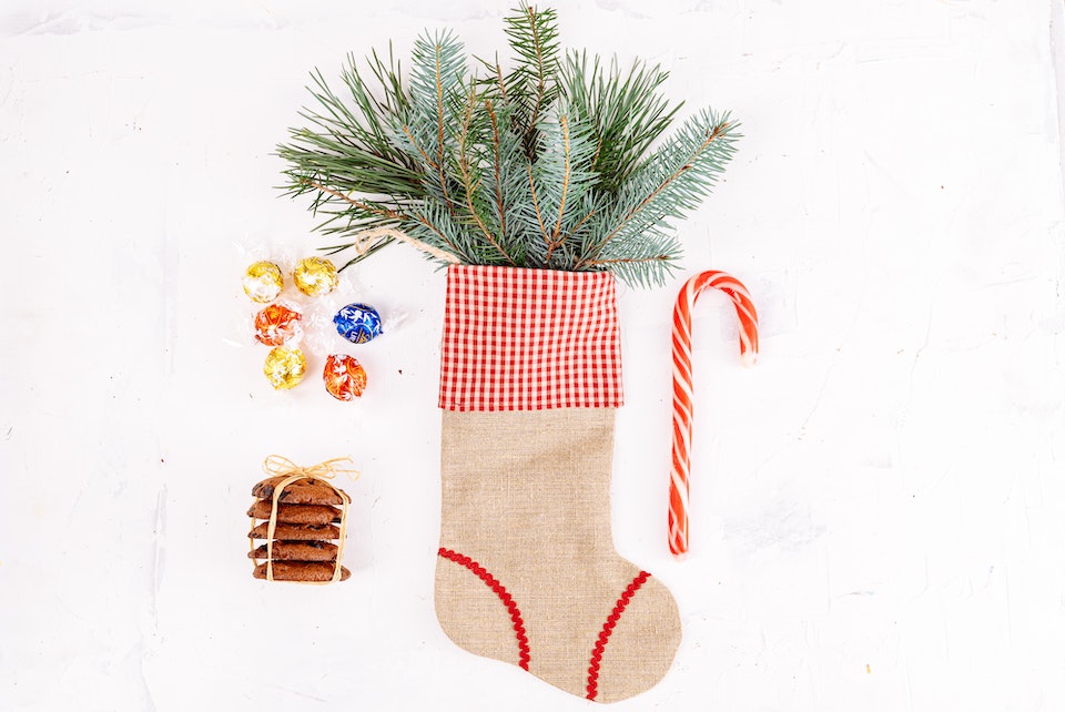 Stocking with cookies, a candy cane, chocolates and pine leaves